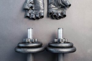 Musculation avec ou sans gants : des haltères et des gants au sol